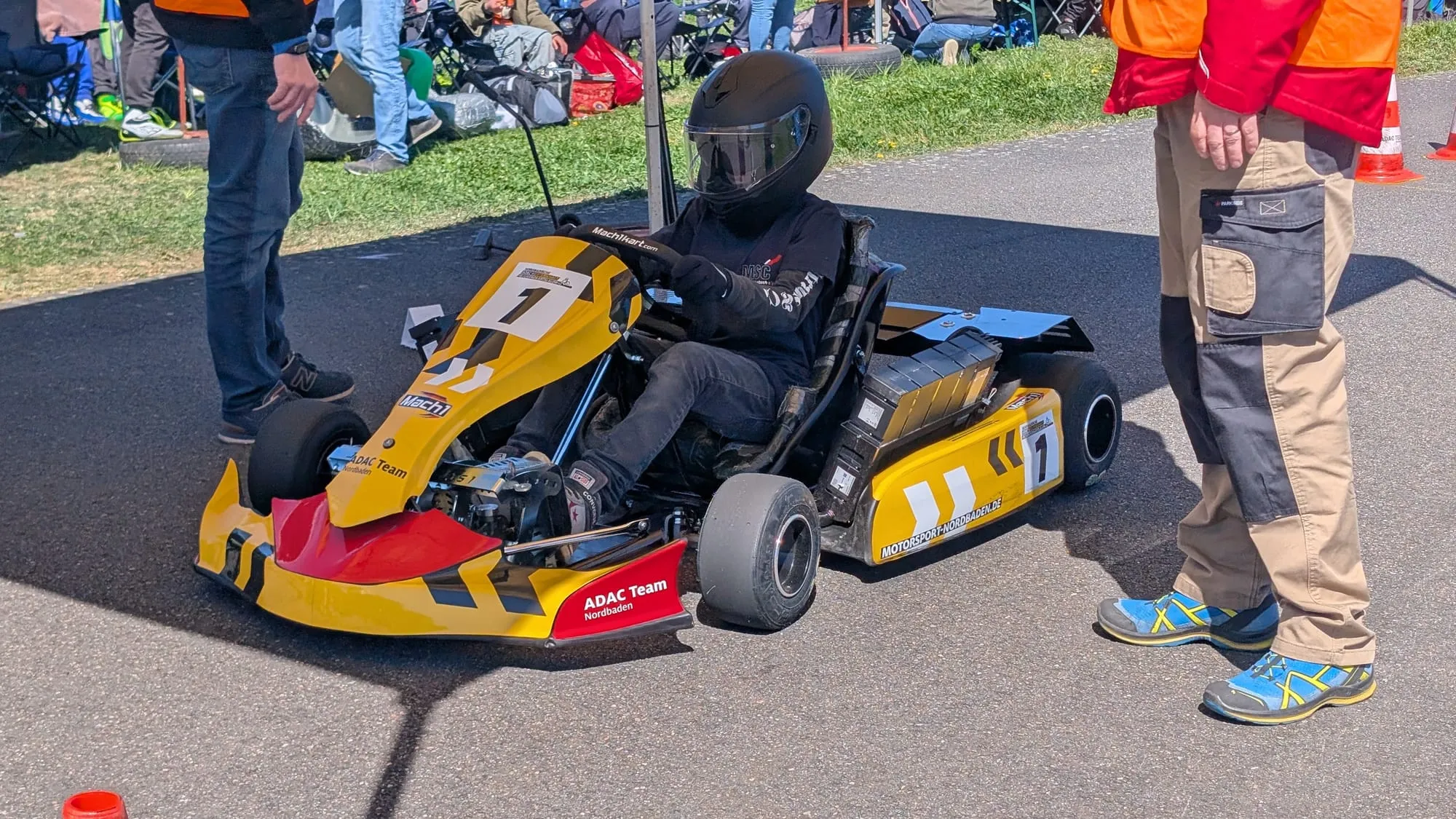 Gelb-blaues ADAC-Elektrokart am Start des Heimlaufs, Betreuer daneben