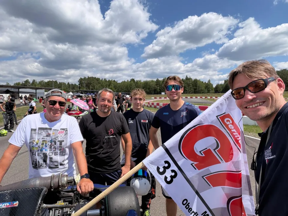 Teammitglieder mit der Fahne der Nummer 33 an der Strecke
