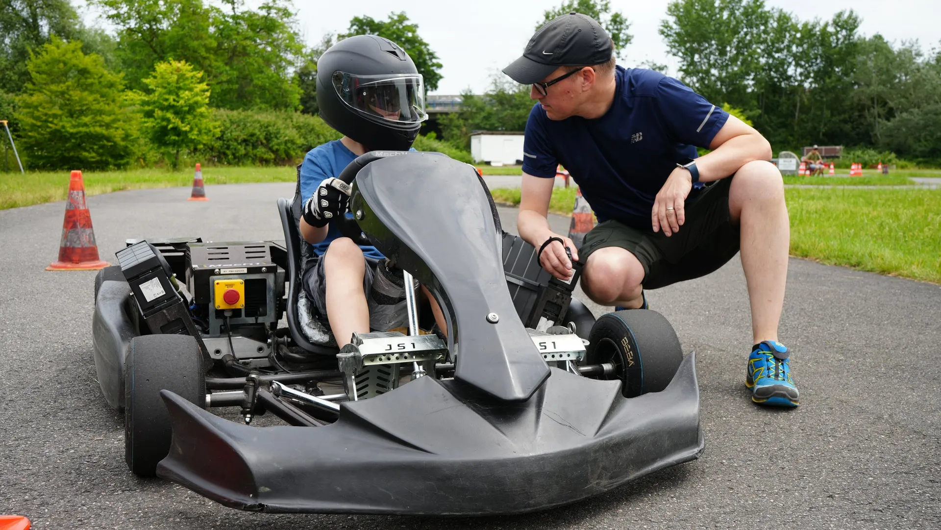 Ein Trainer bespricht mit einem Nachwuchsfahrer im Kart den nächsten Durchgang